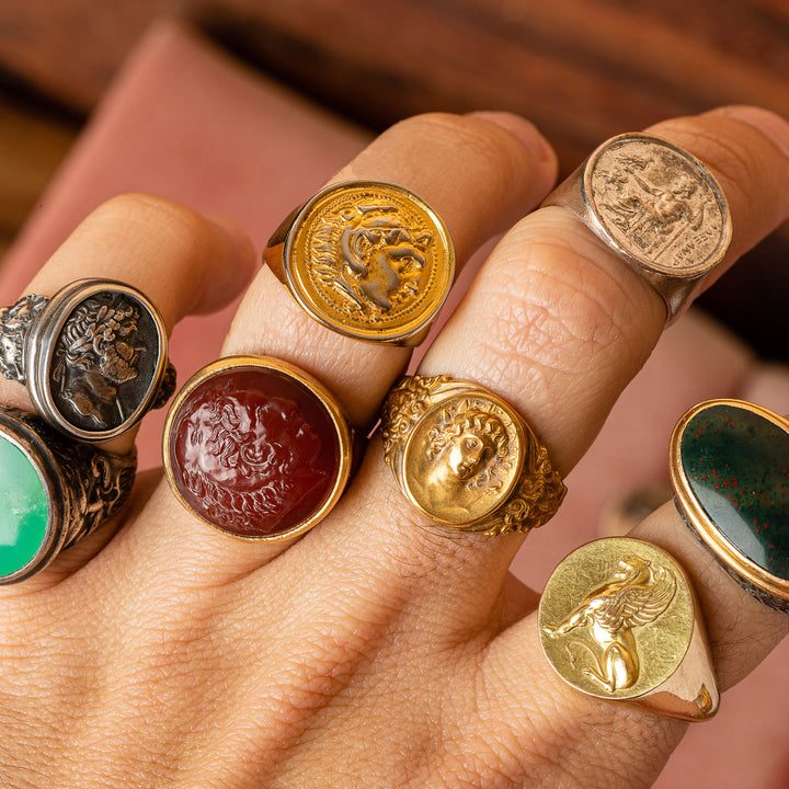 multiple gemstone and metal signet rings on hand